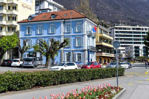 un edificio blu su una strada cittadina con le auto di Hotel Millennium a Locarno