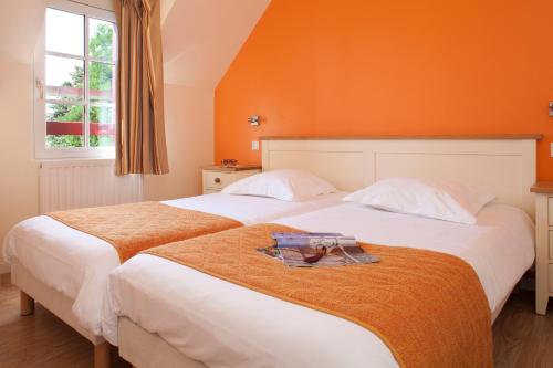 two beds in a bedroom with an orange wall at Le Village Cancalais in Cancale