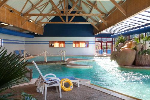 uma grande piscina interior com escorrega num edifício em Le Village Cancalais em Cancale