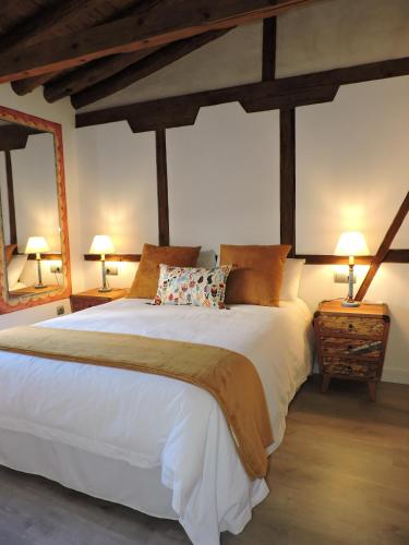 a bedroom with a large white bed with two lamps at El Ático del Nuncio in Toledo