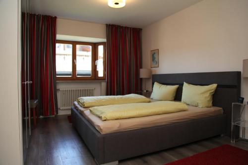 1 dormitorio con 1 cama grande y cortinas rojas en Ferienwohnung Fröhlke, en Oberstdorf