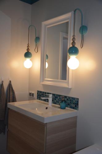 a bathroom with a sink with lights and a mirror at Apartament Pruszków in Pruszków