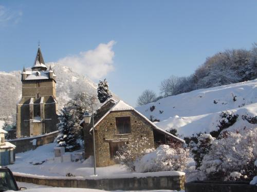an old church with snow on the ground at Hôtel Le Catala in Beaudéan