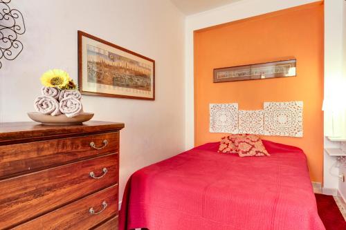 a bedroom with a red bed and a wooden dresser at Paste Apartment in Venice