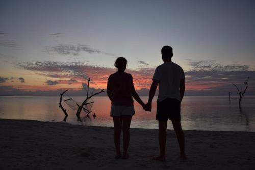 a couple standing on the beach watching the sunset at Araamu Hotels Maldives at Dhiffushi in Dhiffushi