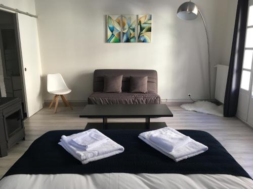 a living room with a bed and two towels at La Maison d'Emilie - Chambres d'hôtes in Chaumes-en-Brie