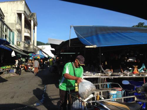 a man in a green shirt standing in a market at Thaweesuk Heritage Homestay in Phangnga