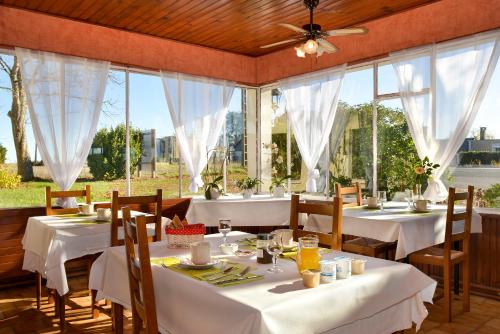 un restaurant avec des tables et des chaises blanches et des fenêtres dans l'établissement Logis Hôtel Restaurant Berry Relais, à Neuvy-Pailloux