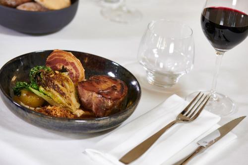 a bowl of food on a table with a glass of wine at Hotel & Spa Vacances Bleues Le Splendid in Dax