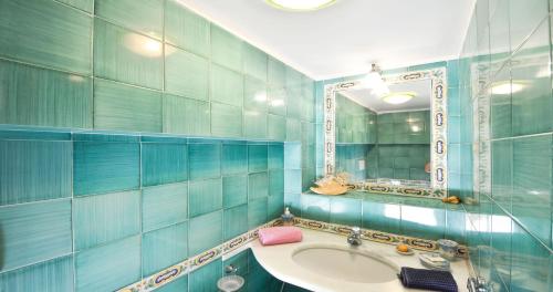a blue tiled bathroom with a sink and a mirror at AMORE RENTALS - Casa Raffi in Positano