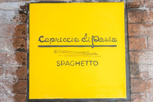 a yellow sign on the side of a brick wall at Capriccio Di Pasta Residence & Spa in Gragnano