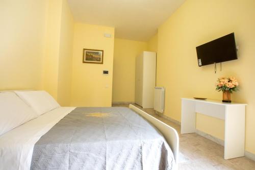 a bedroom with a bed and a tv on the wall at Capriccio Di Pasta Residence & Spa in Gragnano