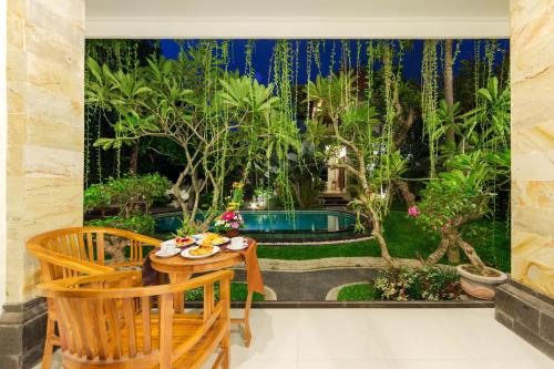 a patio with a table and chairs in a garden at The Tunjung Ubud Retreat in Ubud