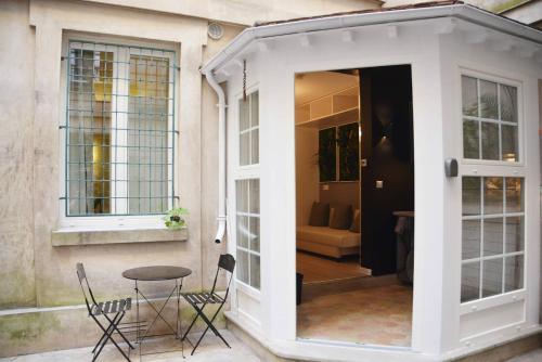 Grenelle - Beautiful flat in central Paris في باريس: فناء مع طاولة وكراسي بجوار مبنى