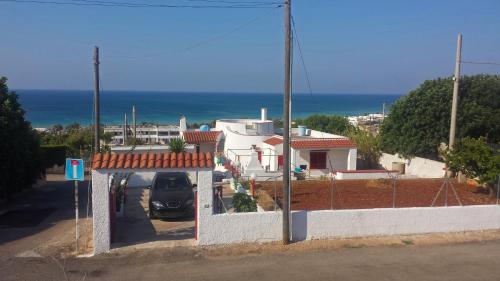 a white house with a car parked in a driveway at Villa Laura Salento in Marina di Pescoluse
