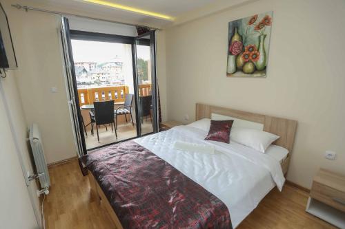a bedroom with a bed and a balcony with a table at Apartment Kristal in Zlatibor