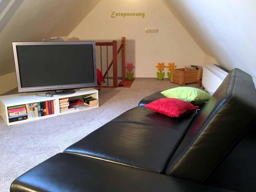 uma sala de estar com um sofá de couro preto e uma televisão em Ferienhaus Finster em Volkach