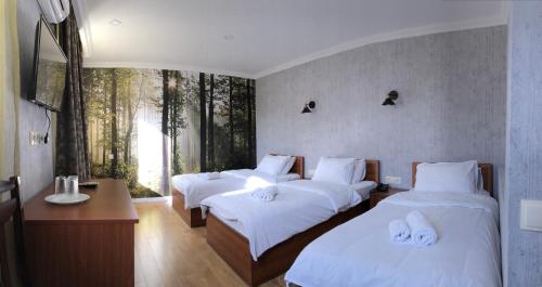 Habitación con 3 camas, sábanas blancas y ventana. en Hotel Kalanga, en Tiflis