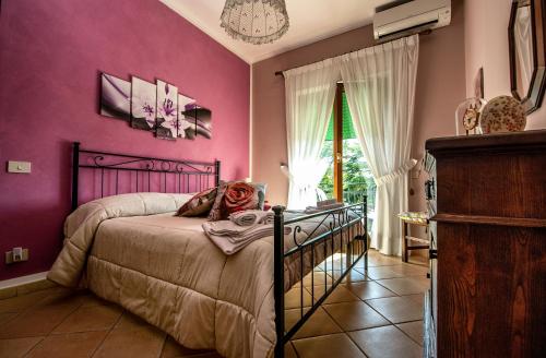 - une chambre avec un lit aux murs violets et une fenêtre dans l'établissement Il Fiore del Golfo, à SantʼAgata sui Due Golfi