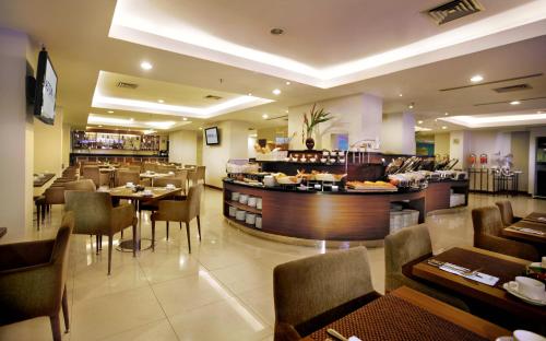 un restaurante con bar y algunas mesas y sillas en ASTON Pluit Hotel & Residence en Yakarta