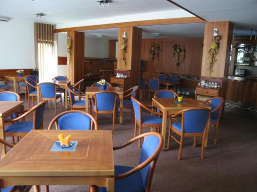 a dining room with wooden tables and blue chairs at Penzion Lázeňský dům in Buchlovice