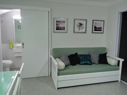 Habitación con baño con sofá verde. en Morada Felice en Bertioga
