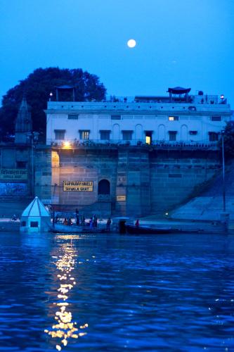 a building next to a body of water at night at Amritara Suryauday Haveli in Varanasi