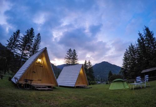 zwei Zelte und Stühle auf einem Feld mit einem Himmel in der Unterkunft Camp Podljubelj in Podljubelj