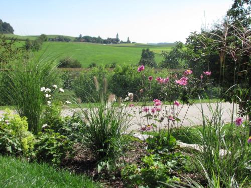 a garden with flowers and a field in the background at Haus Spiessl in Bad Griesbach