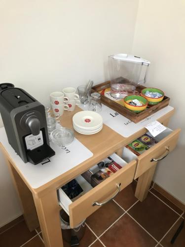 a table with a coffee maker and plates and cups at B&B Au Coeur de Villers in Villers-Sainte-Gertrude
