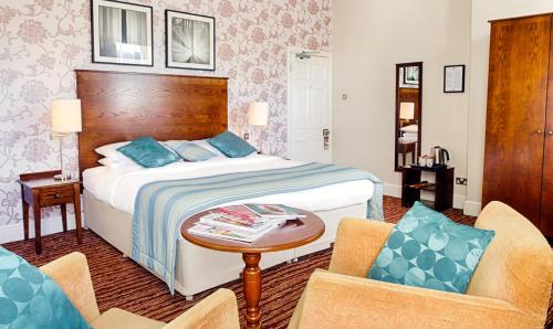a hotel room with a bed and two chairs at White Swan Hotel in Alnwick