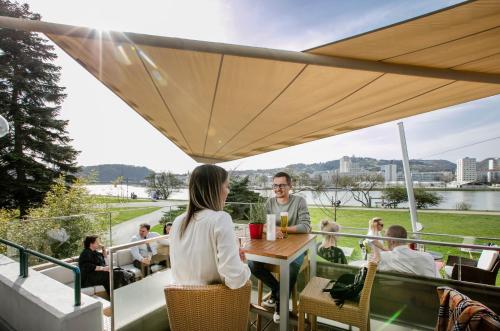 un grupo de personas sentadas alrededor de una mesa en un balcón en ARCOTEL Nike Linz, en Linz