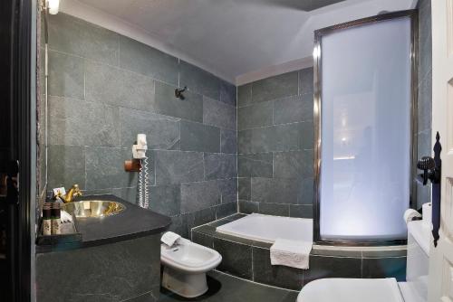 a bathroom with a tub and a toilet and a sink at Apartamentos El Tiempo Madrid in Madrid