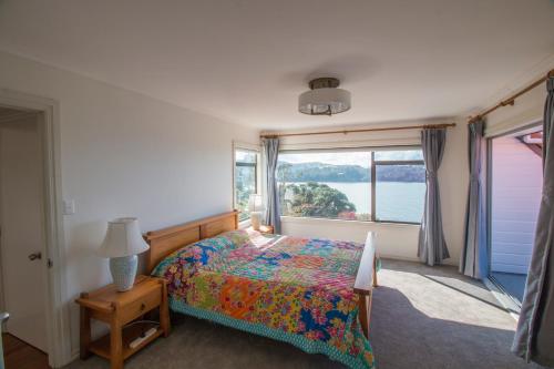 1 dormitorio con cama y ventana grande en Orewa Cliff Top, en Orewa
