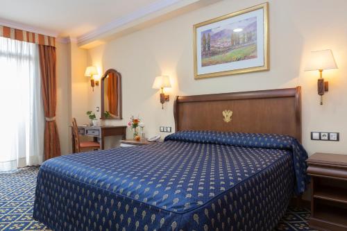 a hotel room with a blue bed and a desk at Agora Juan de Austria in Madrid