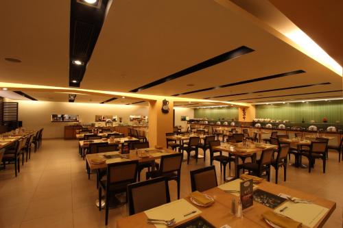 a restaurant with wooden tables and chairs in a room at Minerva Grand Secunderabad in Hyderabad