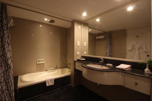 a bathroom with a sink and a tub and a mirror at Minerva Grand Secunderabad in Hyderabad