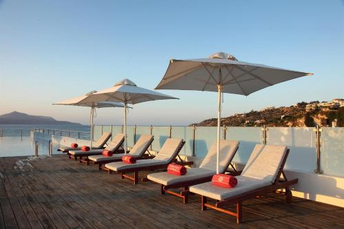 a row of lounge chairs and umbrellas on a pier at Almyrida Resort in Almirida
