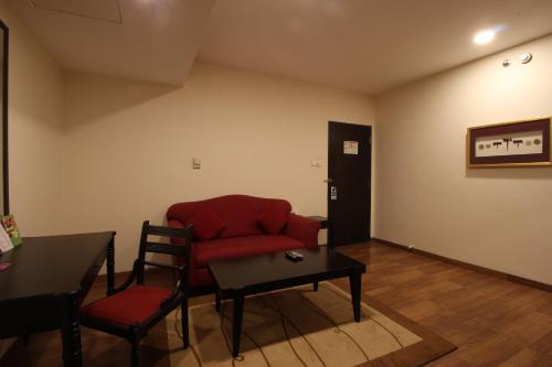 a living room with a red couch and a table at Minerva Grand Secunderabad in Hyderabad