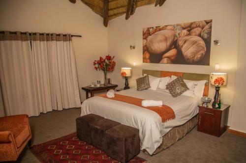1 dormitorio con 1 cama y una pintura en la pared en Gabbata Lodge, en Leeuwfontein