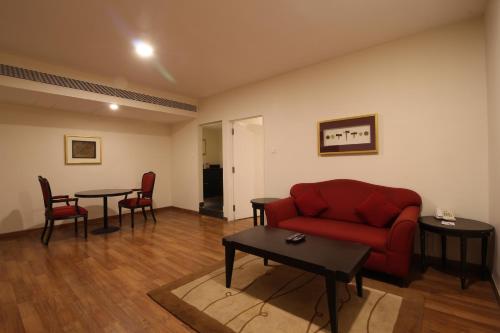 a living room with a red couch and a table at Minerva Grand Secunderabad in Hyderabad