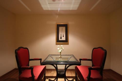a dining room with a glass table and red chairs at Minerva Grand Secunderabad in Hyderabad