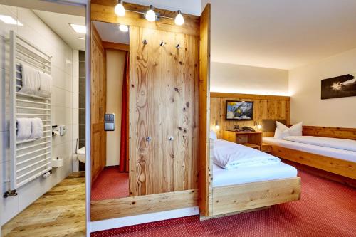 a bedroom with a wooden wall with a bed and a mirror at Hotel Franziska in Mittenwald