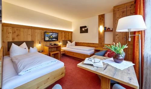 a hotel room with two beds and a table at Hotel Franziska in Mittenwald