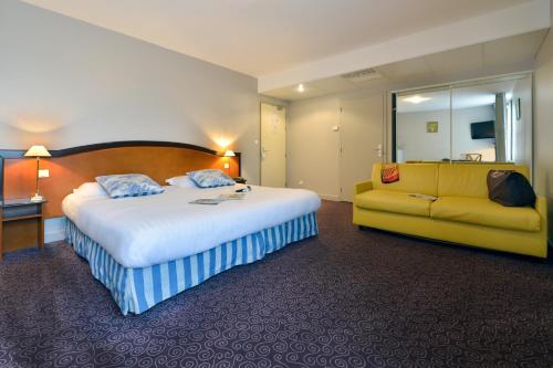 a hotel room with a bed and a yellow couch at Soleil et Jardin in Solaize