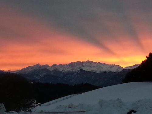 a sunset in the mountains with snow on the ground at Panoramahotel Obkircher in Nova Ponente