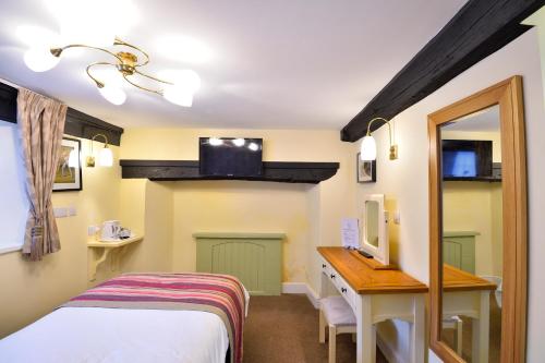 a room with a bed and a desk with a mirror at The Royal Victoria and Bull Hotel in Dartford