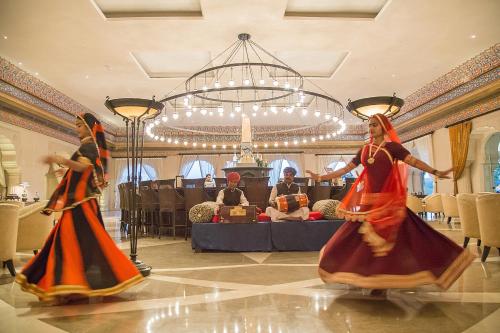 two women in colorful dresses dancing in a room at Fairmont Jaipur in Jaipur