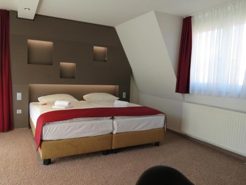 a bedroom with a large bed with red and white sheets at Hotel Neuthor in Ulm