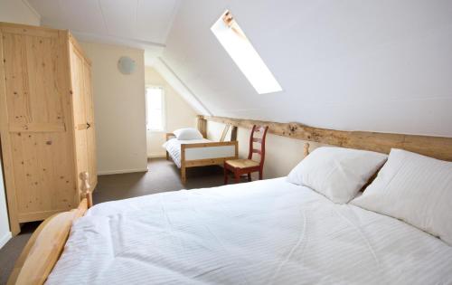 a bedroom with a white bed and a chair at De Toffe Peer Recreatie in Ruinerwold